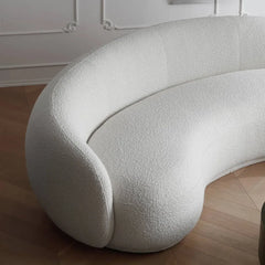 Curved sofa with wraparound backrest and deep bench seating, wide-angle seating view