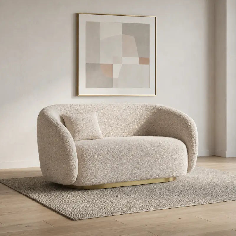 Curved sofa with brushed gold base and rounded supportive arms, left-side view