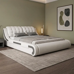 A modern white upholstered bed with a tufted headboard and sculptural side details, styled in a minimalist bedroom with gray bedding, a gray rug, and olive green walls.