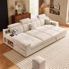 A large cream-colored modular sectional sofa with tufted cushions, styled in a warm, modern living room with a patterned rug, wooden floor, and built-in shelving.