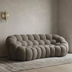 Lounge sofa with thick rounded cushions and padded arms, front three-quarter view