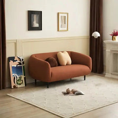 Curved sofa with wraparound backrest and compact seating, front three-quarter view