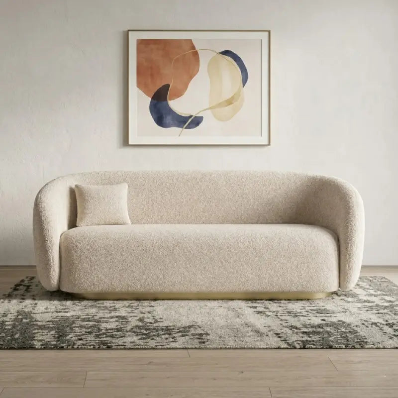 Boucle sofa with brushed gold base and rounded supportive arms, straight front view