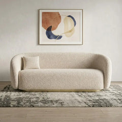 Boucle sofa with brushed gold base and rounded supportive arms, straight front view