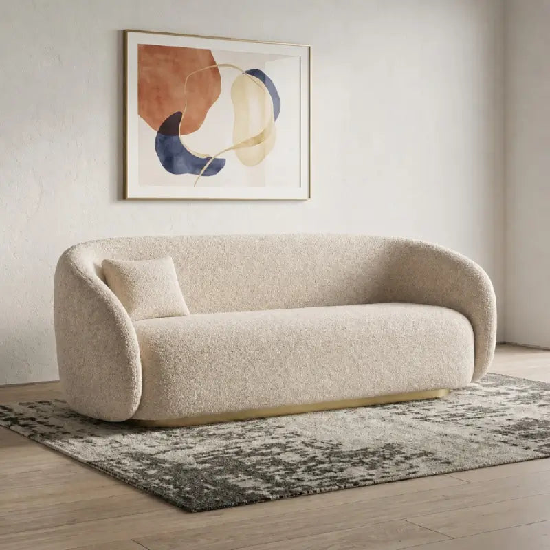 Curved sofa with brushed gold base and rounded supportive arms, front three-quarter view