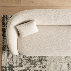 Boucle sofa with brushed gold base and rounded supportive arms, close-up of seat cushions