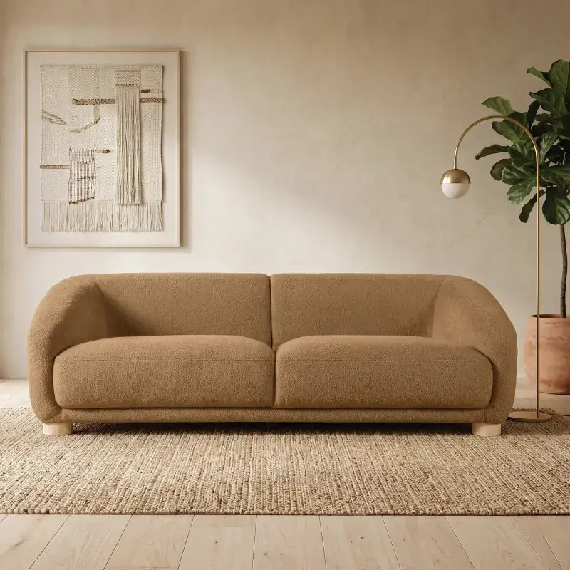 Fabric sofa with thick rounded arms and natural wooden legs, left-side view