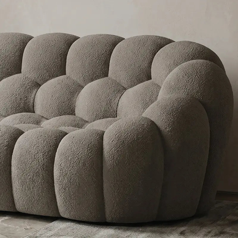 Boucle sofa with thick rounded cushions and padded arms, close-up of seat cushions