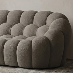 Boucle sofa with thick rounded cushions and padded arms, close-up of seat cushions