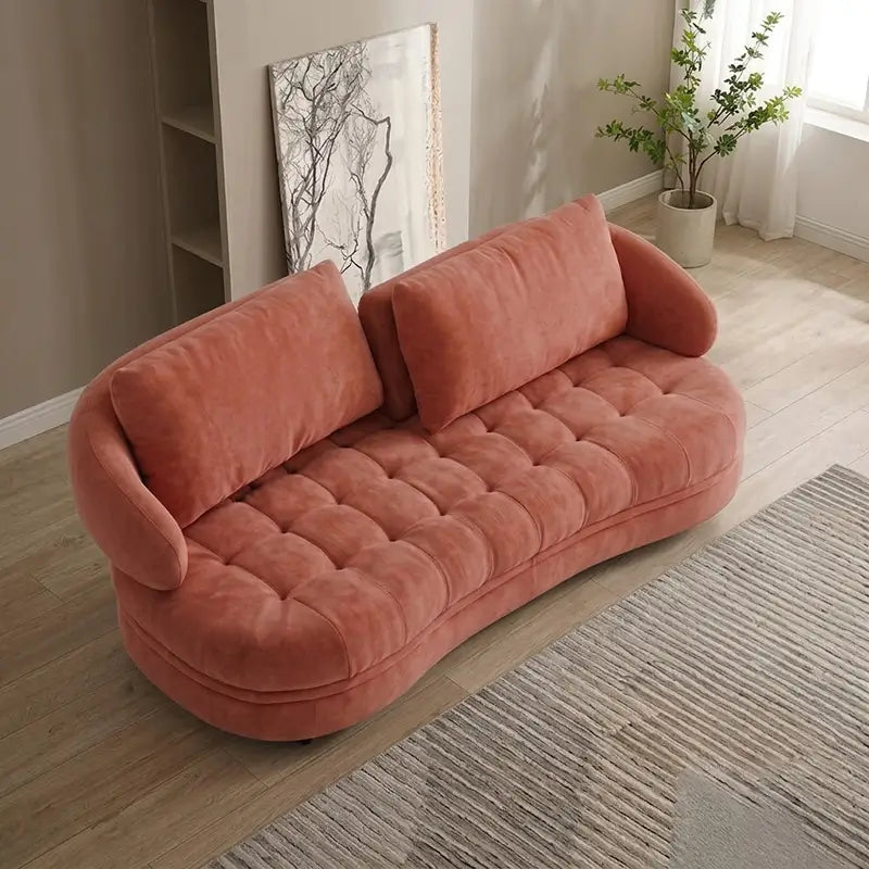 Upholstered in coral pink velvet-look fabric, this fabric sofa combines a modern sofa design with the relaxed proportions of a lounge sofa
